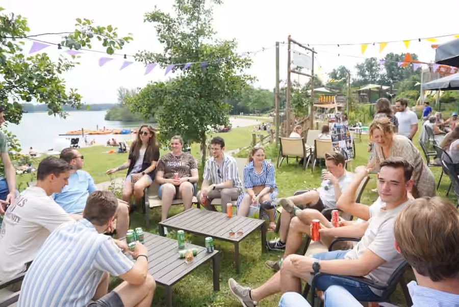 Bezoekers zitten samen op het tuinterras aan het water.